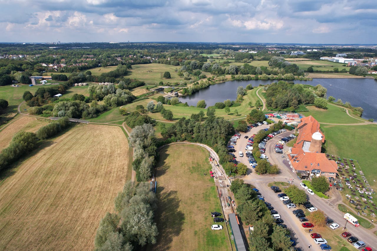 Aerial shot of Caldecotte Lake, lush greenery, and countryside in England.